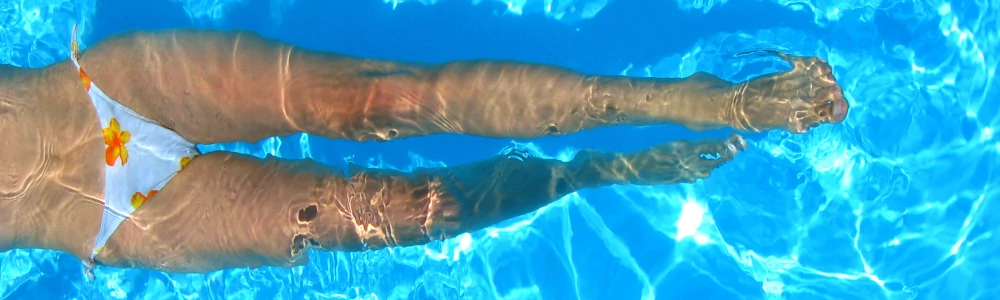 Zdjęcie nóg w basenie w słoneczny dzień.